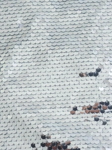 Macro di paillettes circolari d'argento sovrapposte con riflessi metallici brillanti