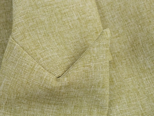Macro detail of the light green linen-like textured fabric on a two-piece pant suit