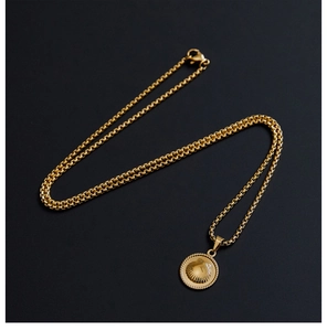 Detail of 18K gold-plated shell engraved coin pendant on box chain over black background