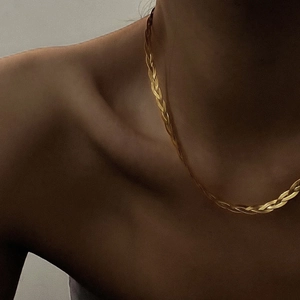 Elegant gold braided titanium necklace on a model showing a high-end minimalist woven choker
