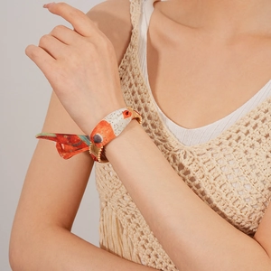 Detail of silk scarf bracelet with gold metal buckle worn with beige crochet top