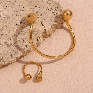 Detail view of gold open bracelet and ring set with drop-shaped ends on natural stone