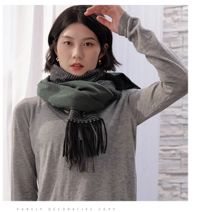 Close-up of winter scarf featuring dark green plaid pattern and long black fringe details