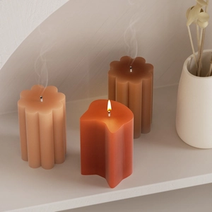 Bougies parfumées aux formes géométriques irrégulières dans une niche minimaliste chaleureuse