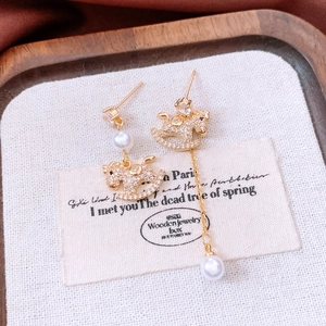 Detail of 18k gold plated rocking horse earrings with pearls and zircon tassels