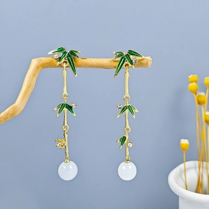 Detail of vintage bamboo tassel earrings with green enamel leaves and white beads
