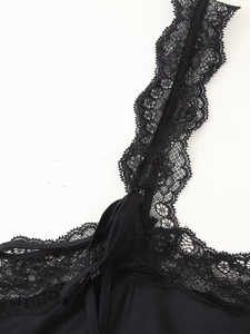 Dettaglio ravvicinato della spallina in pizzo nero su un abito sottoveste in raso nero
