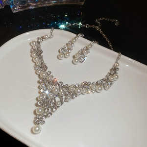 Détail du parure collier et boucles d'oreilles avec perles et strass brillants sur plateau