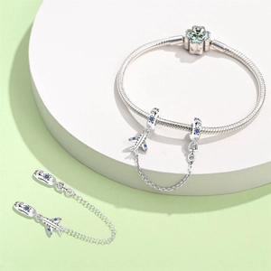 Detail of silver snake chain bracelet with airplane safety chain and clover clasp