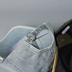 Close-up of adjustable strap with vintage copper buckle on washed denim baseball cap