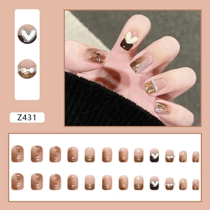 Press-on nails featuring marble finish gold foil heart accents and pearl jewelry details