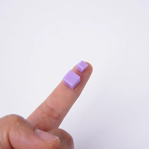 Miniatuur paarse PVC suikerblokjes voor DIY taartdecoratie met vinger als schaalmodel