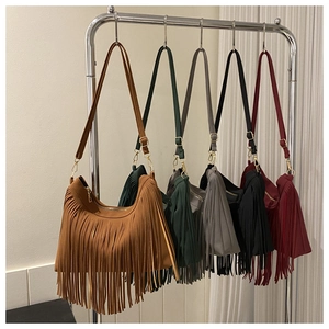 Detailed view of five colorful suede bucket bags with long fringes on metal hangers