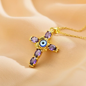 Golden cross necklace with purple oval gemstones and evil eye center on silk background