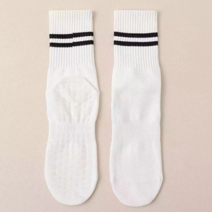 White crew yoga socks with black stripes and anti-slip grips on beige background