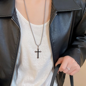 Detail of cross pendant necklace with black enamel center on silver metal chain