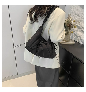 Detailed view of black nylon dumpling bag featuring drawstring base and ruched shoulder strap
