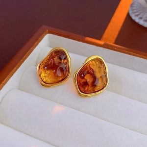 Close-up of vintage geometric tiger eye resin earrings with gold-plated metal edges