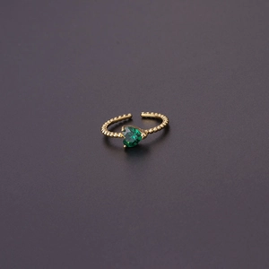 Detailed close-up of a golden heart-shaped ring with green zircon and beaded band