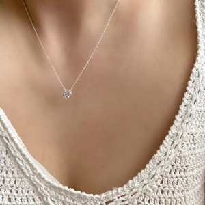 Detail of 925 sterling silver heart necklace with zircon on a model's collarbone