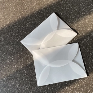 Dettaglio di buste in carta velina traslucida con design di chiusura a forma di petalo