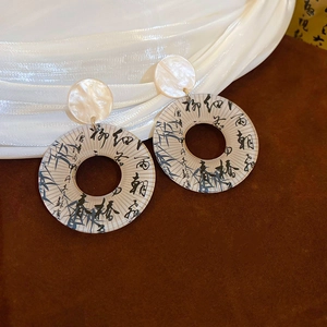 Detail of Chinese style earring with calligraphy on translucent acrylic ring and gold connector