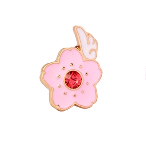 Pink enamel cherry blossom brooch with white wings and red rhinestone center detail
