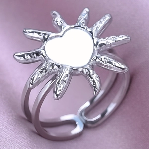 Macro detail of silver sun heart adjustable ring on purple silk fabric background