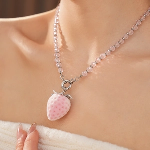 Close-up of pink strawberry pendant necklace with silver and transparent beads
