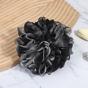 Large black bamboo charcoal bath sponge with white mesh edges on a marble surface