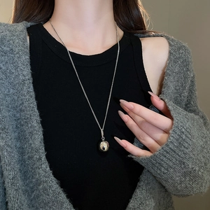 Close-up of minimalist silver stainless steel ball pendant necklace worn by a model