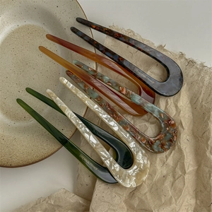 Classic U-shaped acetate hair pins in various colors displayed on a ceramic plate