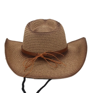 Detail of straw cowboy hat featuring leather trim, gradient texture and adjustable chin strap