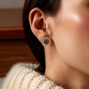 Detailed view of round 18k gold plated earring with white and black zircon on model