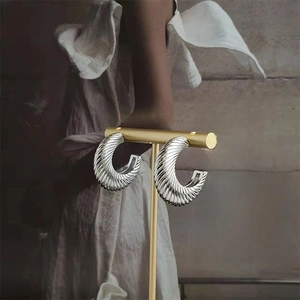 Detailed view of silver spiral textured hoop earrings on a gold T-shaped jewelry display stand