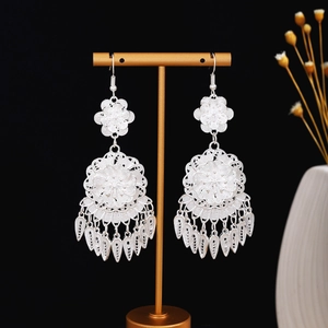 Dettaglio di orecchini a nappa lunga in argento con fiori traforati su un espositore