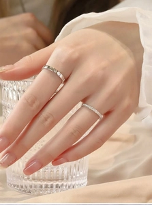 Detail of stacked silver screw motif ring and slim sparkling diamond band on hand