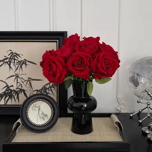 Elegant red velvet roses in a sleek black ceramic vase on a textured tray centerpiece