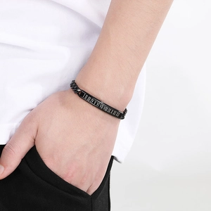 Detail of men's black stainless steel bracelet with Roman numeral engraved plate