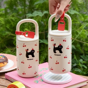 Close-up of portable coffee storage tin featuring cute black cat and cherry patterns
