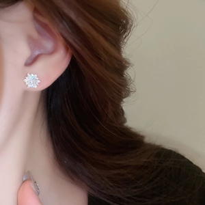 Close-up of minimalist silver snowflake earrings with sparkling cubic zirconia on model