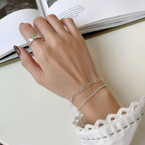 Dettaglio del bracciale a catena in argento S925 e anello strutturato con pietre verdi