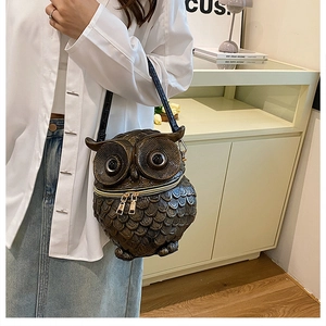 Detailed view of owl-shaped relief crossbody bag with bronze texture and feather patterns