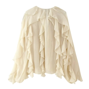 Gros plan détaillé des volants superposés sur une blouse beige en mousseline à manches longues