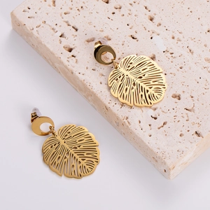 French vintage style gold monstera leaf earrings with hollow texture on a stone