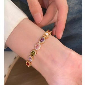 French style gold bracelet with colorful oval gemstones and zircon accents on wrist