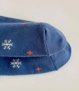 Close-up of navy blue knit Christmas socks with white and orange snowflake patterns
