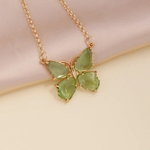 Macro detail of golden butterfly necklace with green zircon crystals on silk fabric