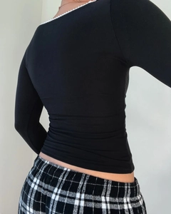 Detail view of long-sleeve black top featuring elegant white lace neckline trim on the back