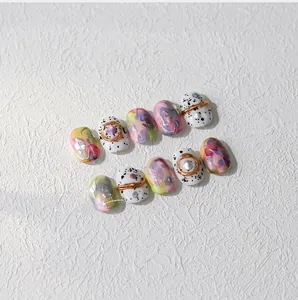 Detail of macaron nail stickers with gold wire, pearls, and iridescent sequins decoration